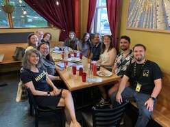 IRC staff and volunteers sit around a table smiling during Welcoming Week event.